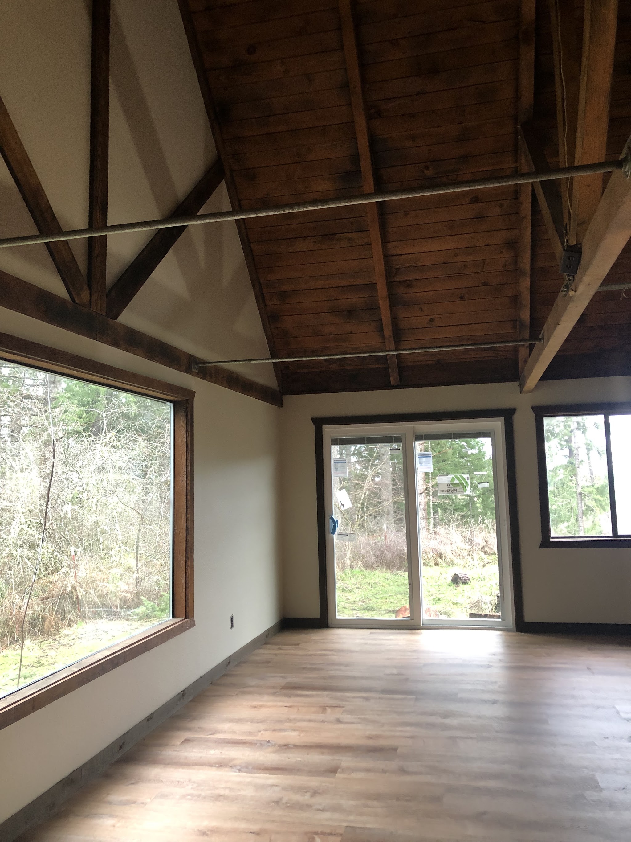 Vaulted-ceiling room mid-renovation with exposed wood beams and new windows