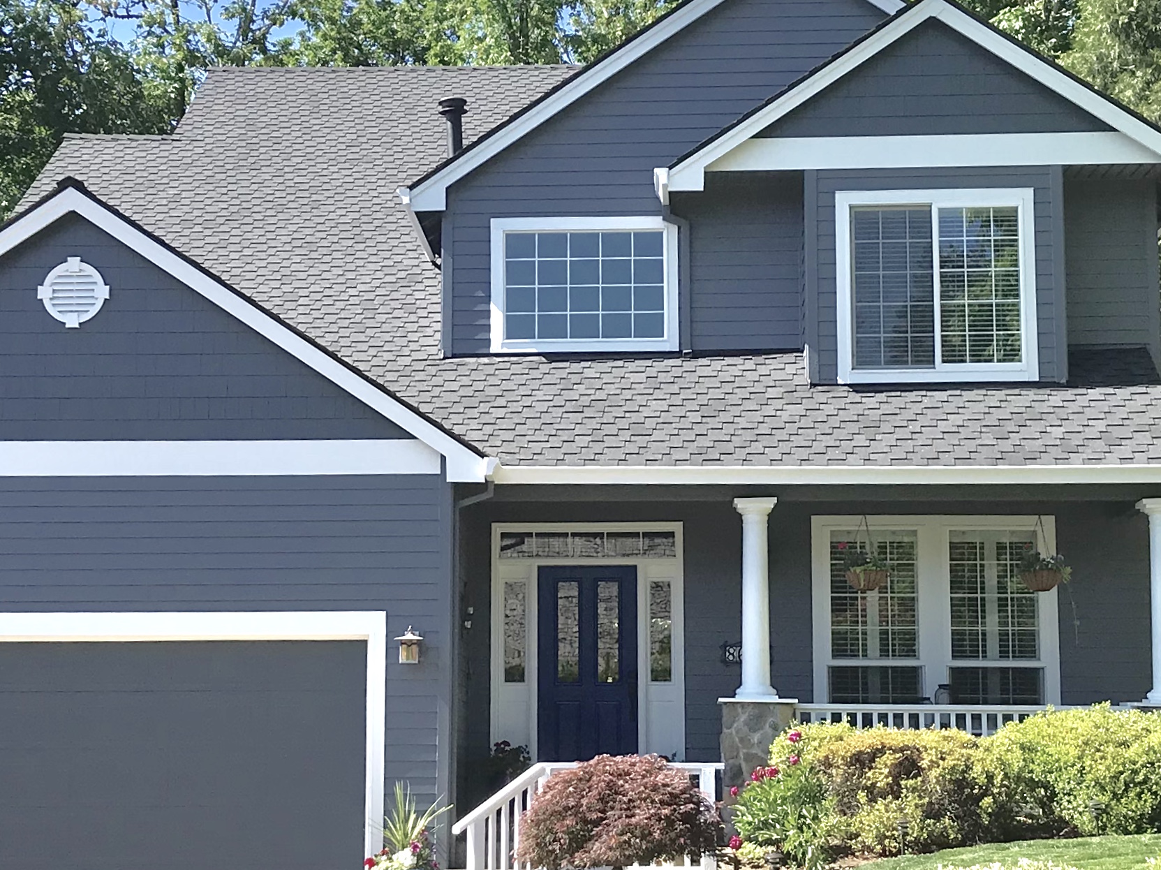 A finished exterior paint job on a two-story navy blue home with white trim